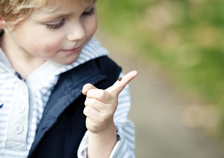 Ein kleiner Junge zeigt etwas im Freien. Er lächelt.