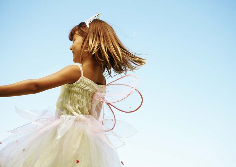Ein Mädchen in einem rosa Kleid, das sich im Wind dreht. Sie trägt ein weißes Haarband.