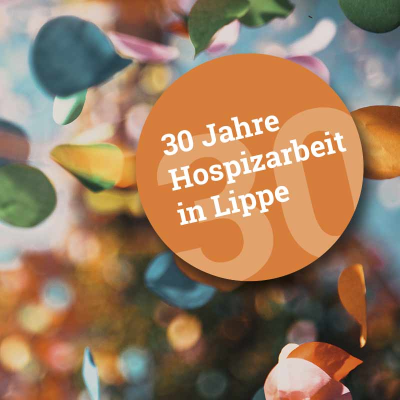 Ein großes oranges Kreis mit der Aufschrift 30 Jahre Hospizarbeit in Lippe vor einem bunte Hintergrund