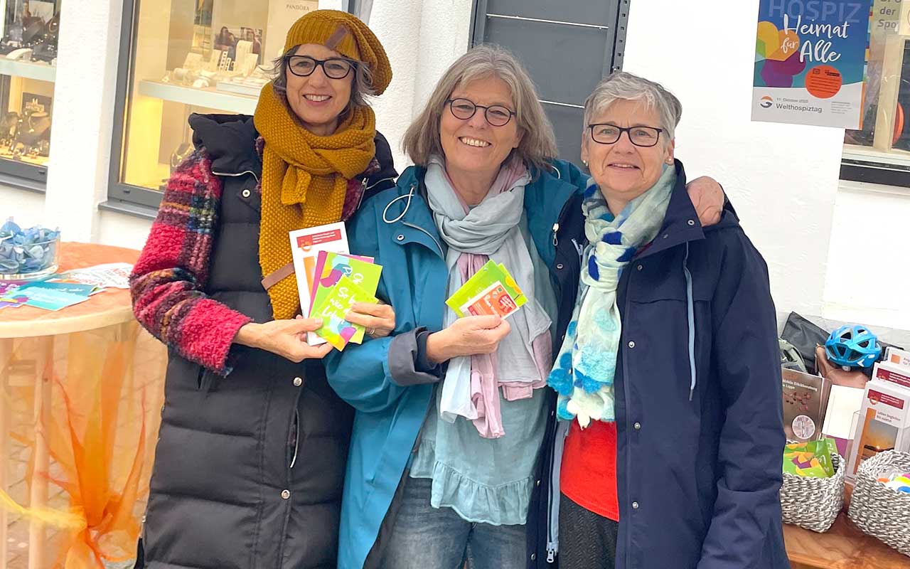 Drei Frauen halten Bücher in den Händen und lächeln.