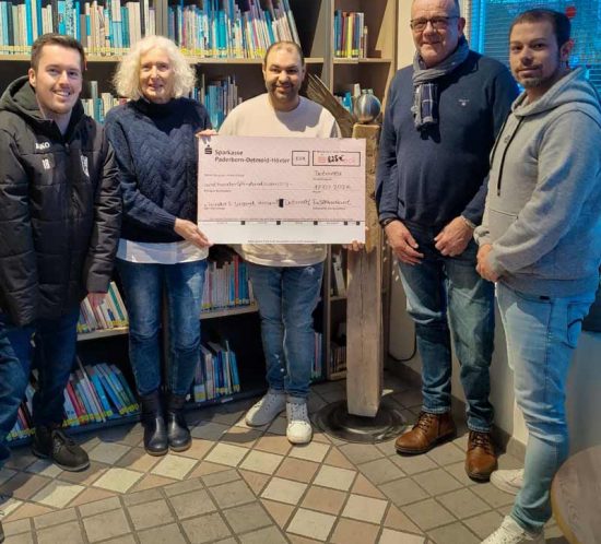 Ein großes Team hält einen Spendenscheck