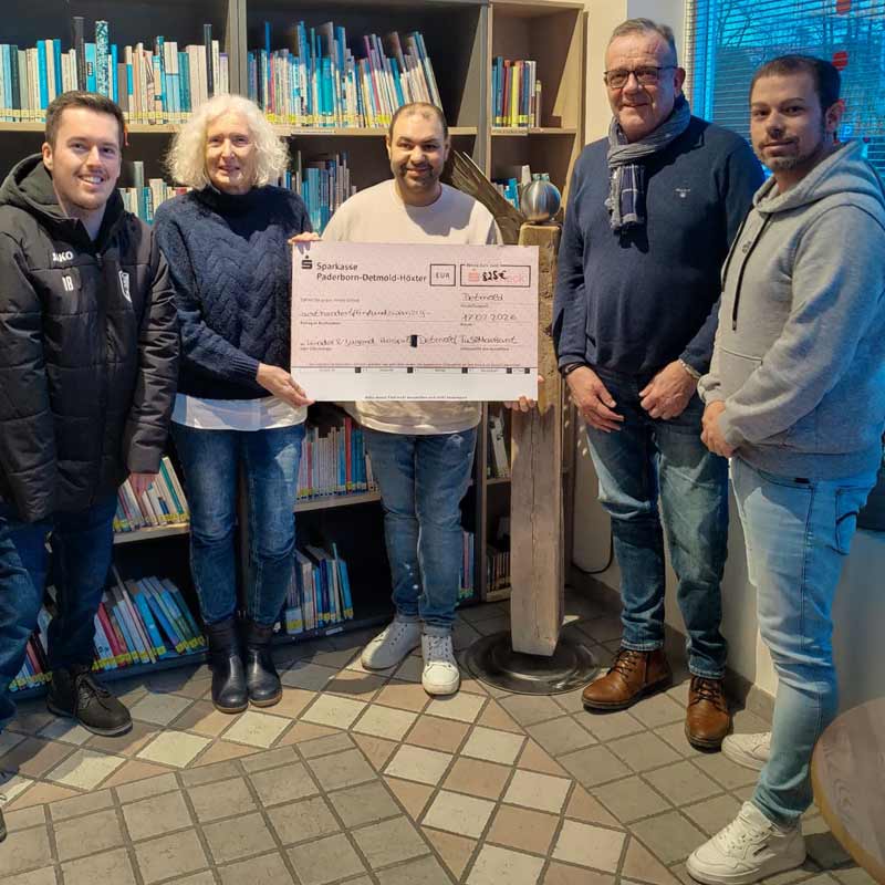 Ein großes Team hält einen Spendenscheck