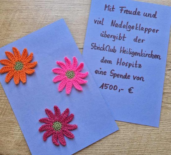 Eine blaue Karte mit drei handgemachten Blumen und ein Brief mit einer Spende von 500 Euro
